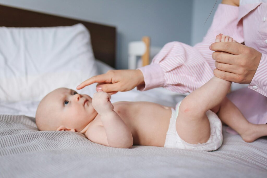 Parent gently massaging infant’s legs on a soft blanket to promote bonding and relaxation